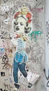 Multi-textured street art showing a woman's face cut out of a photo and various grafitti behind her